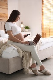 Pregnant woman working on bed at home. Maternity leave