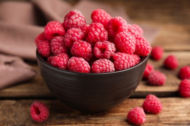 Bowl with fresh ripe raspberries on wooden table, closeup