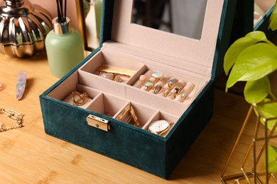Elegant jewelry box with beautiful bijouterie and expensive wristwatch on wooden table