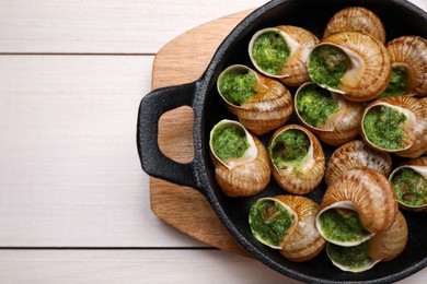 Delicious cooked snails served on white wooden table, top view. Space for text