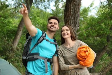 Image of Young couple with traveling gear near camping tent in forest