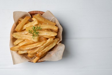 Photo of Bowl of french fries on white wooden table, top view. Space for text