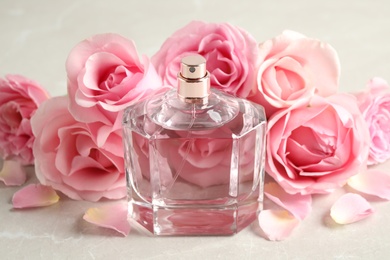 Bottle of perfume and beautiful roses on light table