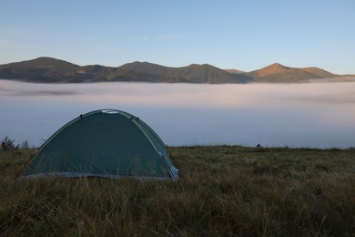 Picturesque mountain landscape with camping tent in foggy morning. Space for text