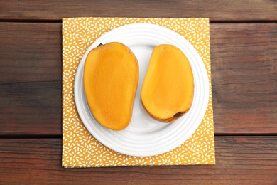Delicious cut ripe mangos on wooden table, top view