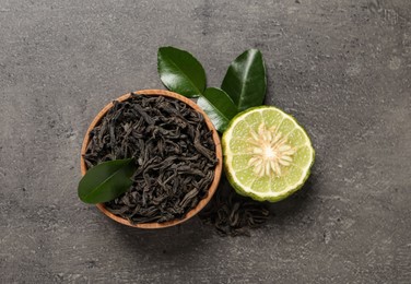 Dry bergamot tea leaves and fresh fruit on grey table, flat lay