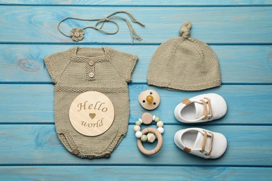 Flat lay composition with cute baby knitwear for photoshoot on light blue wooden background