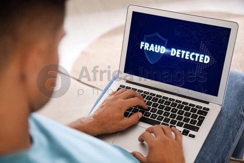 Fraud prevention security system. Man using laptop at home, closeup
