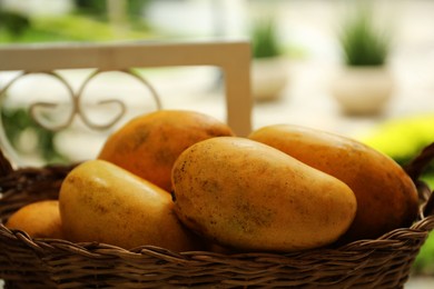 Basket with delicious ripe yellow mangos outdoors, closeup