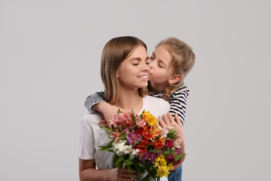 Photo of Little daughter congratulating her mom with flowers on white background. Happy Mother's Day