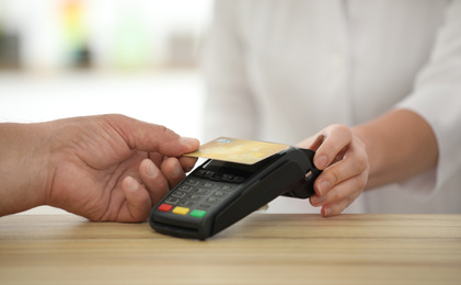 Photo of Customer using terminal for contactless payment with credit card in pharmacy, closeup