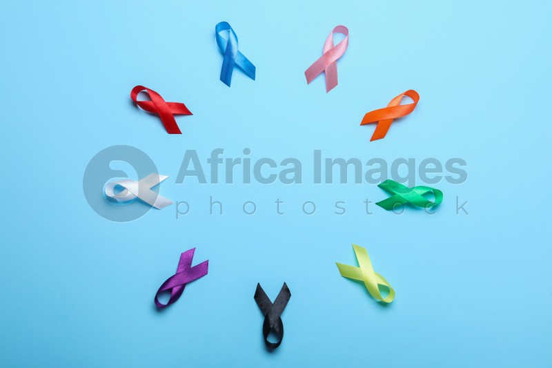 Photo of Frame of colorful ribbons on light blue background, flat lay with space for text. World Cancer Day