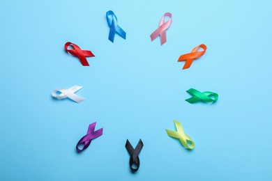 Frame of colorful ribbons on light blue background, flat lay with space for text. World Cancer Day