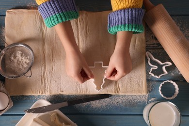 Little child cutting Christmas cookies at blue wooden table, top view