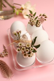 Photo of Festive composition with eggs and floral decor on pink background, above view. Happy Easter