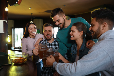 Group of friends celebrating victory of favorite football team in sport bar