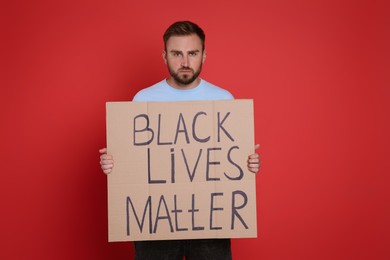 Young man holding sign with phrase Black Lives Matter on red background. End racism