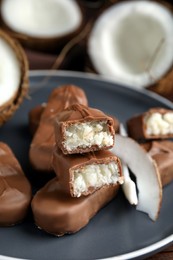 Delicious milk chocolate candy bars with coconut filling on grey plate, closeup
