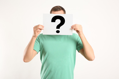 Man holding paper with question mark on white background
