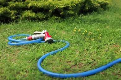 Photo of Watering hose with sprinkler on green grass outdoors