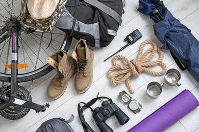 Flat lay composition with sleeping bag, bicycle and camping equipment on wooden background