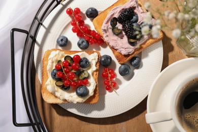 Cup of coffee near sandwiches with cream cheese and berries on tray, flat lay