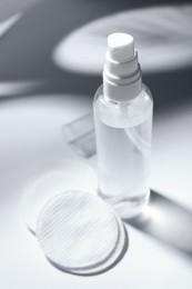 Bottle of micellar water and cotton pads on white table