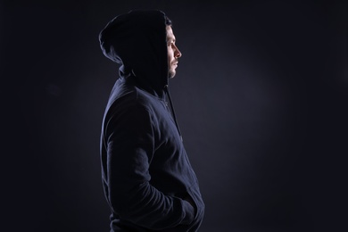 Photo of Mysterious man in hoodie on dark background. Dangerous criminal