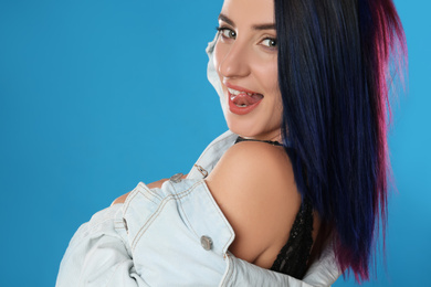 Young woman with bright dyed hair on blue background, closeup