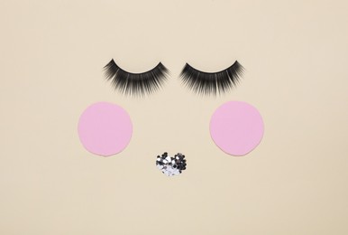 Photo of False eyelashes, pink paper circles and sequins as beautiful face on beige background, flat lay