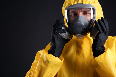 Man wearing chemical protective suit on black background, closeup. Virus research