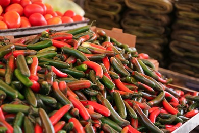 Heap of fresh Serrano peppers on counter at market, space for text