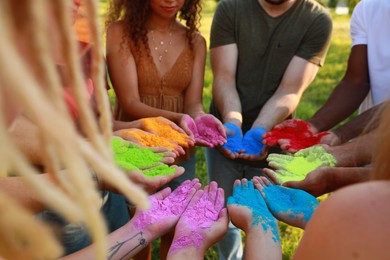 Photo of Friends with colorful powder dyes outdoors, closeup. Holi festival celebration