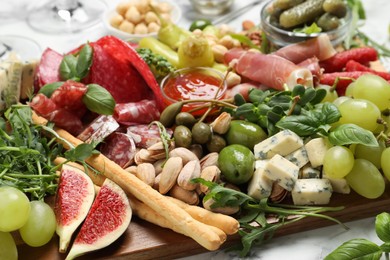 Photo of Set of different delicious appetizers on wooden board, closeup