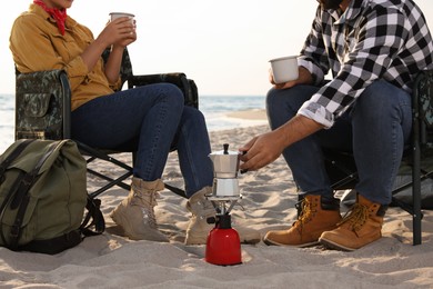 Couple resting in camping chairs on beach, closeup. Making coffee