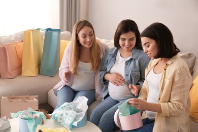 Happy pregnant women spending time together in living room after shopping