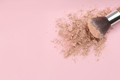 Photo of Makeup brush and scattered face powder on pink background, top view. Space for text