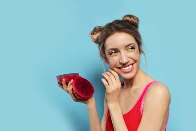 Photo of Young woman with fresh pitahaya on light blue background, space for text. Exotic fruit