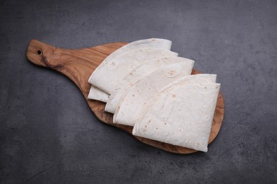 Photo of Delicious folded Armenian lavash on dark table, top view