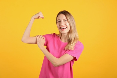 Strong woman as symbol of girl power on yellow background. 8 March concept