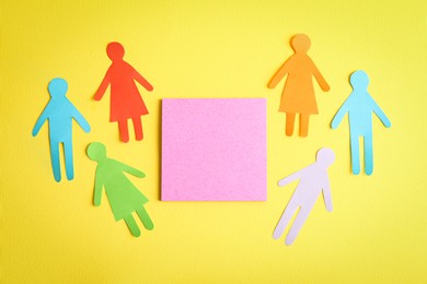 Many different paper human figures around blank card on yellow background, flat lay with space for text. Diversity and inclusion concept