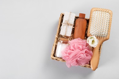 Spa gift set with different products in wicker box on light grey background, top view. Space for text