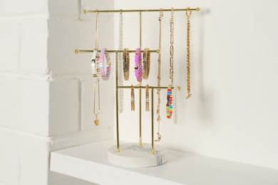 Holder with set of luxurious jewelry on white shelf