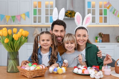 Photo of Portrait of happy family with Easter eggs at table in kitchen
