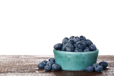 Bowl with tasty fresh blueberries on wooden table against white background