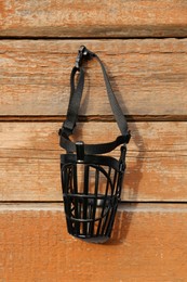 Photo of Black dog muzzle hanging near wooden fence
