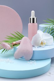 Photo of Beautiful composition with gua sha stone, face roller and bottle of serum on light background