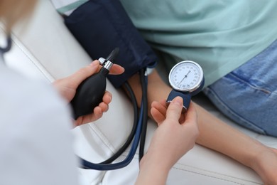 Doctor checking blood pressure of woman in clinic, closeup