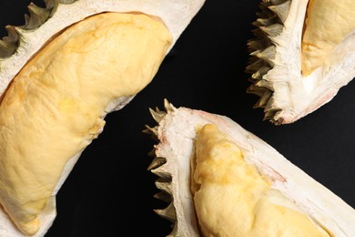 Pieces of fresh ripe durian on black background, flat lay
