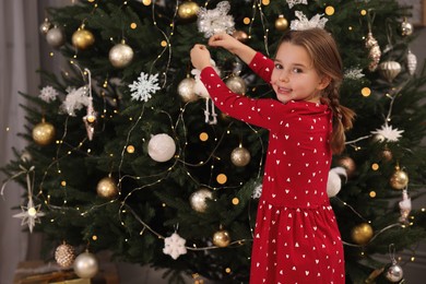 Cute little child decorating Christmas tree at home